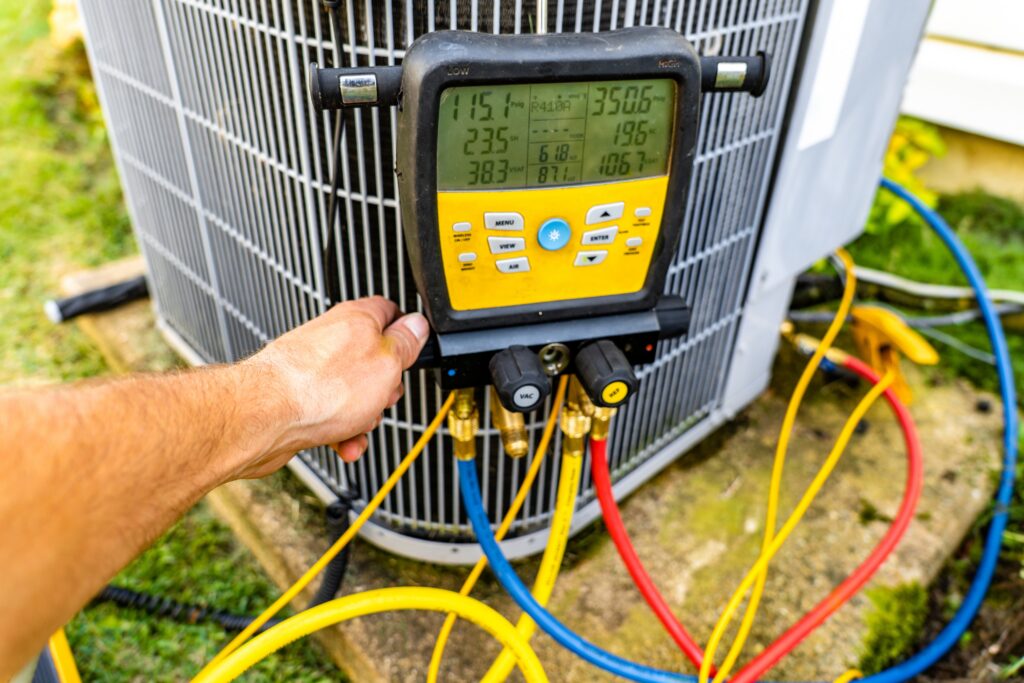 Dowd Heating & Air Conditioning technician checking refrigerant pressure and system performance during residential AC repair service on an outdoor air conditioning unit.
