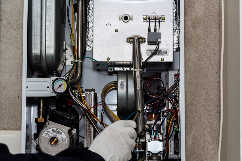 HVAC technician working inside a residential furnace during professional heating system installation and setup