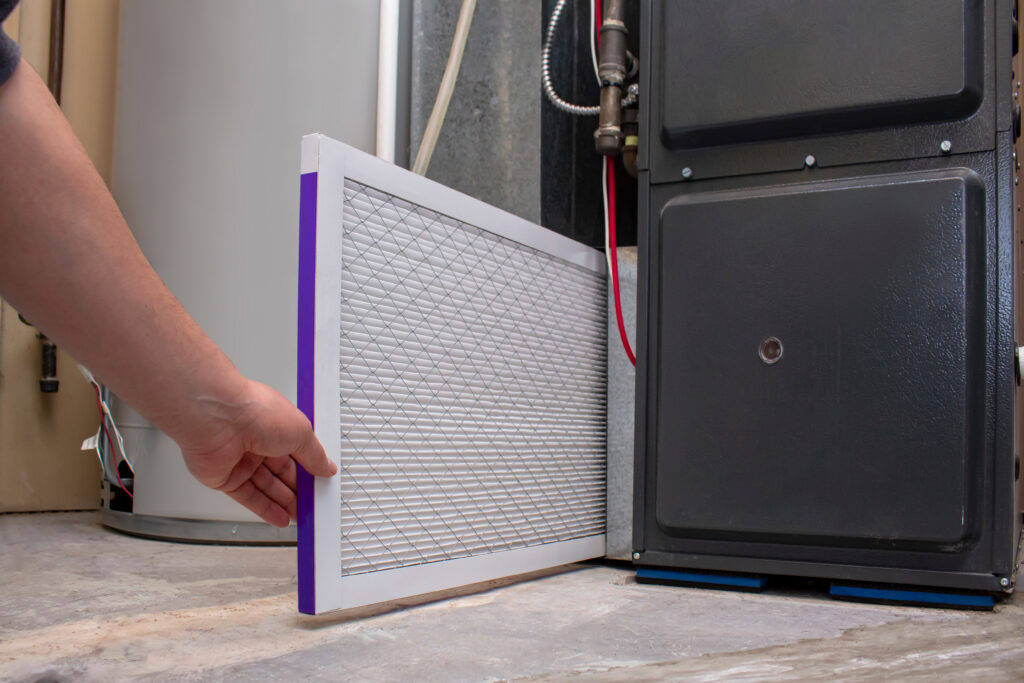 Technician replacing a furnace air filter during routine residential heating system maintenance